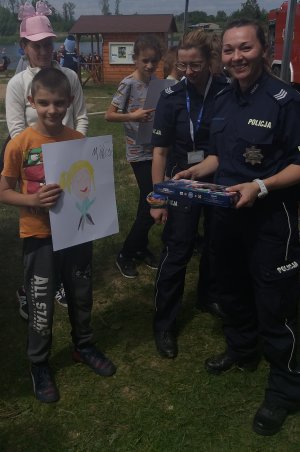 Chłopiec z nagrodą, którą dostał od policjantki za wykonany rysunek