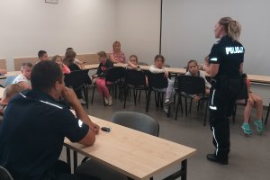 Policjantka opowiadająca dzieciom o bezpiecznych zachowaniach podczas wakacji