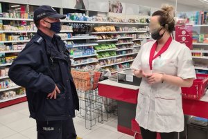 policjant rozmawiający z kobietą pracującą w jednym z chełmińskich sklepów, podczas zadań związanych z kontrolą stosowania się do przepisów związanych z pandemią