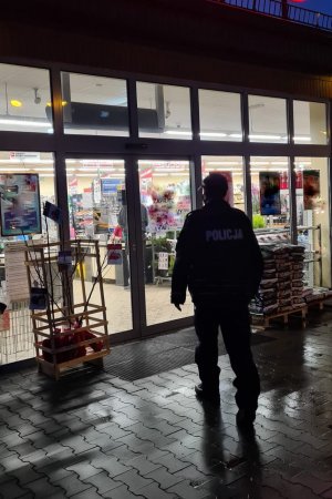 Policjant stoi przed wejściem do obiektu handlowego