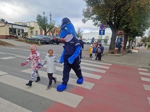 Polfin przeprowadza dzieci przez jezdnię na przejściu dla pieszych