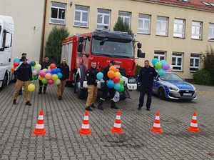 policjanci i strażacy stoją z balonami