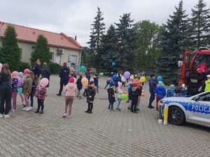 dzieci stoją na placu przed szkołą z kolorowymi balonami