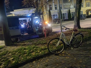 rower stoi na chodniku w pobliżu policyjnego radiowozu