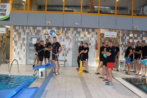 uczestnicy zawodów stoją przy basenie