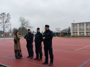 policjanci i kobieta stoją na boisku szkolnym