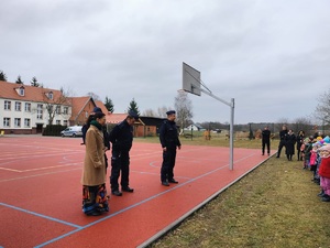 policjanci i kobieta stoja na boisku szkolnym