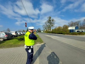 policjant ruchu drogowego kontroluje prędkość jadących pojazdów w obszarze zabudowanym