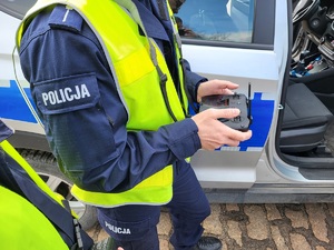 policjant trzyma w ręku panel sterowania dronem
