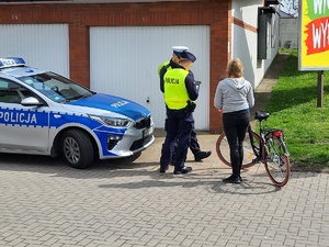policjanci legitymują uczestniczkę ruchu drogowego która trzyma rower