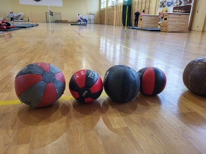 piłki lekarskie ustawione na parkiecie sali gimnastycznej